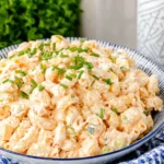 Close-up bowl of Macaroni Hawaiian Salad with creamy elbow pasta, carrots, celery, and fresh chives on top