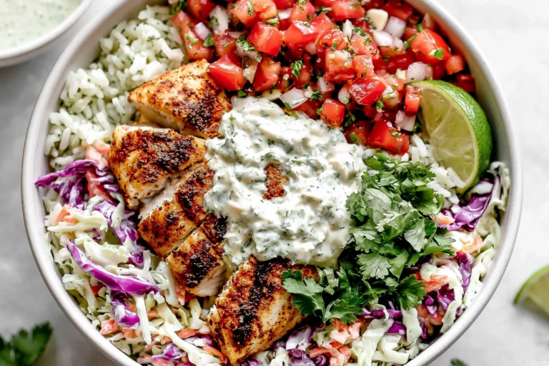 Mahi Mahi Taco Bowls topped with seasoned air-fried mahi mahi, cilantro lime crema, pico de gallo, cabbage slaw, cilantro lime rice, fresh cilantro, and lime wedges.
