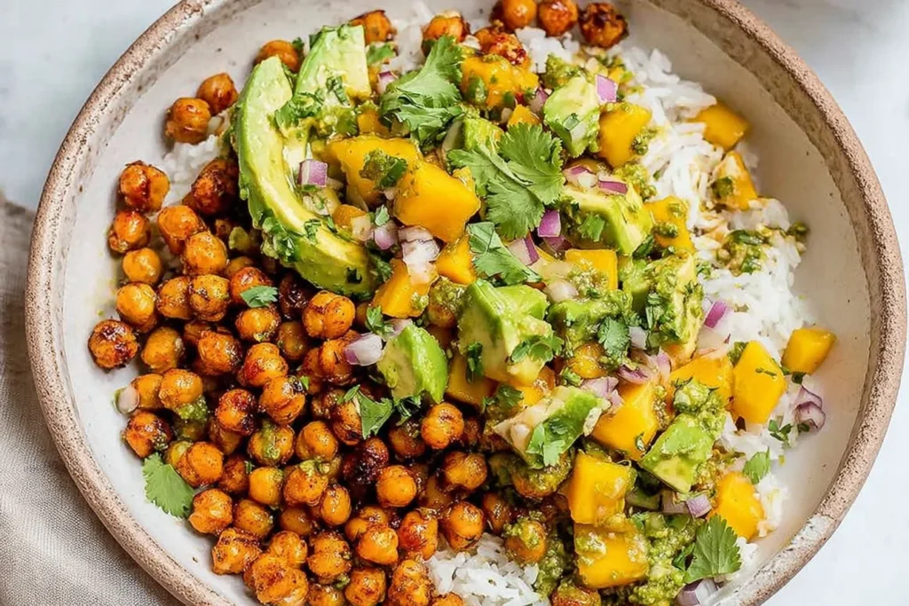 Mango Chickpea Salad bowl with crispy roasted chickpeas, fluffy rice, creamy avocado, juicy mango, red onion, cilantro, and lime.