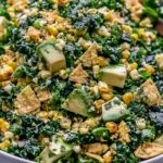 Mexican Street Corn Kale Salad made with grilled corn, fresh kale, creamy avocado, cotija cheese, red onion, and crunchy tortilla chips tossed in a zesty cilantro lime dressing.