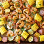 Sheet Pan Shrimp Boil baked on a sheet pan with Old Bay shrimp, corn rounds, baby potatoes, sliced andouille sausage, and lemon.