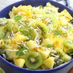 Pineapple Kiwi Salad in a blue bowl with honey-lime glaze, fresh mint, and toasted coconut.