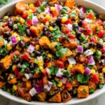 Roasted Sweet Potato Black Bean Salad with roasted sweet potatoes, black beans, corn, red bell peppers, red onion, cilantro, and lime dressing in a serving bowl.