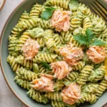 Salmon Pesto Pasta served with flaky roasted salmon, rotini pasta coated in vibrant basil pesto, and fresh lemon wedges for an easy weeknight dinner.