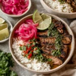 Skirt Steak Rice Bowls with Chimichurri Sauce with sliced grilled steak, white rice, pickled red onions, fresh herbs, and lime wedges.