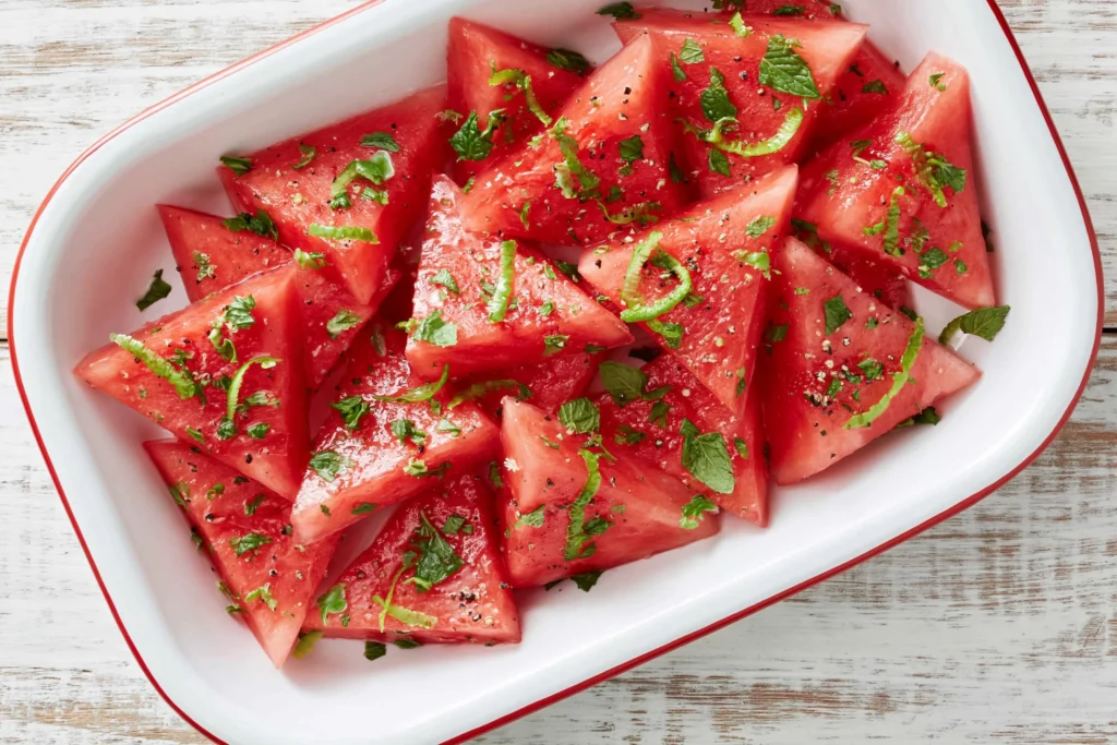 Mojito Watermelon with fresh mint, lime zest, and a light citrus dressing served in a white dish for a refreshing summer side.