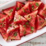 Mojito Watermelon with fresh mint, lime zest, and a light citrus dressing served in a white dish for a refreshing summer side.