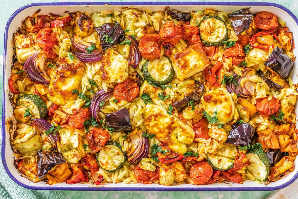 Baked Orzo Roasted Mediterranean Vegetables with Halloumi in a baking dish with roasted tomatoes, zucchini, red onion, eggplant, orzo, and golden halloumi.