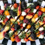 Summer Fruit Caprese Salad with peaches, heirloom tomatoes, fresh mozzarella, basil, blackberries, raspberries, and balsamic glaze on a serving platter.